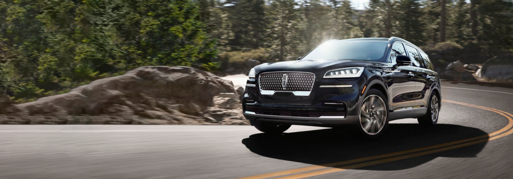 Luxurious black SUV navigating a scenic winding forest road, showcasing elegance and performance.